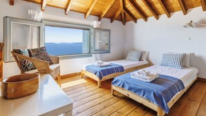 A room with two wooden beds, a large window with a view, a wooden ceiling, and a white table with a bowl. - Villa Kalyves Armenopetra - Beautiful  Pool - Amazing Sea Views -Walk to Beaches (Neo Klima)