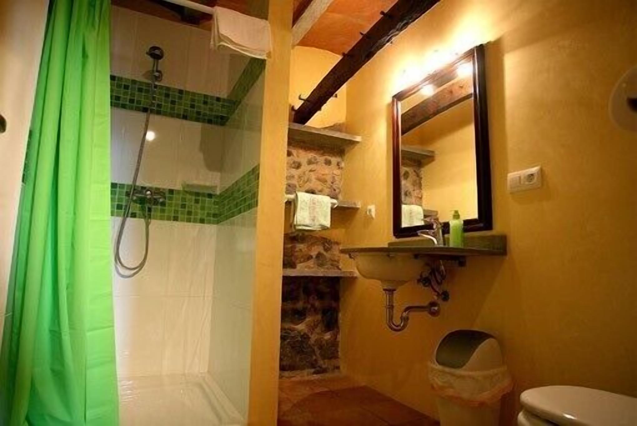 A bathroom with a shower, a sink, a mirror, and a toilet.