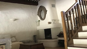 Ein gemütliches Wohnzimmer mit Kamin, einer Holztreppe und einem dekorativen Spiegel an der Wand.