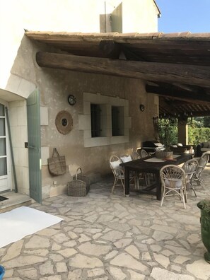 Une terrasse extérieure dotée d'un sol en pierre, de meubles en osier et d'un style architectural rustique.