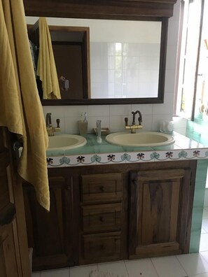 Une salle de bain avec deux lavabos, un miroir et une fenêtre.