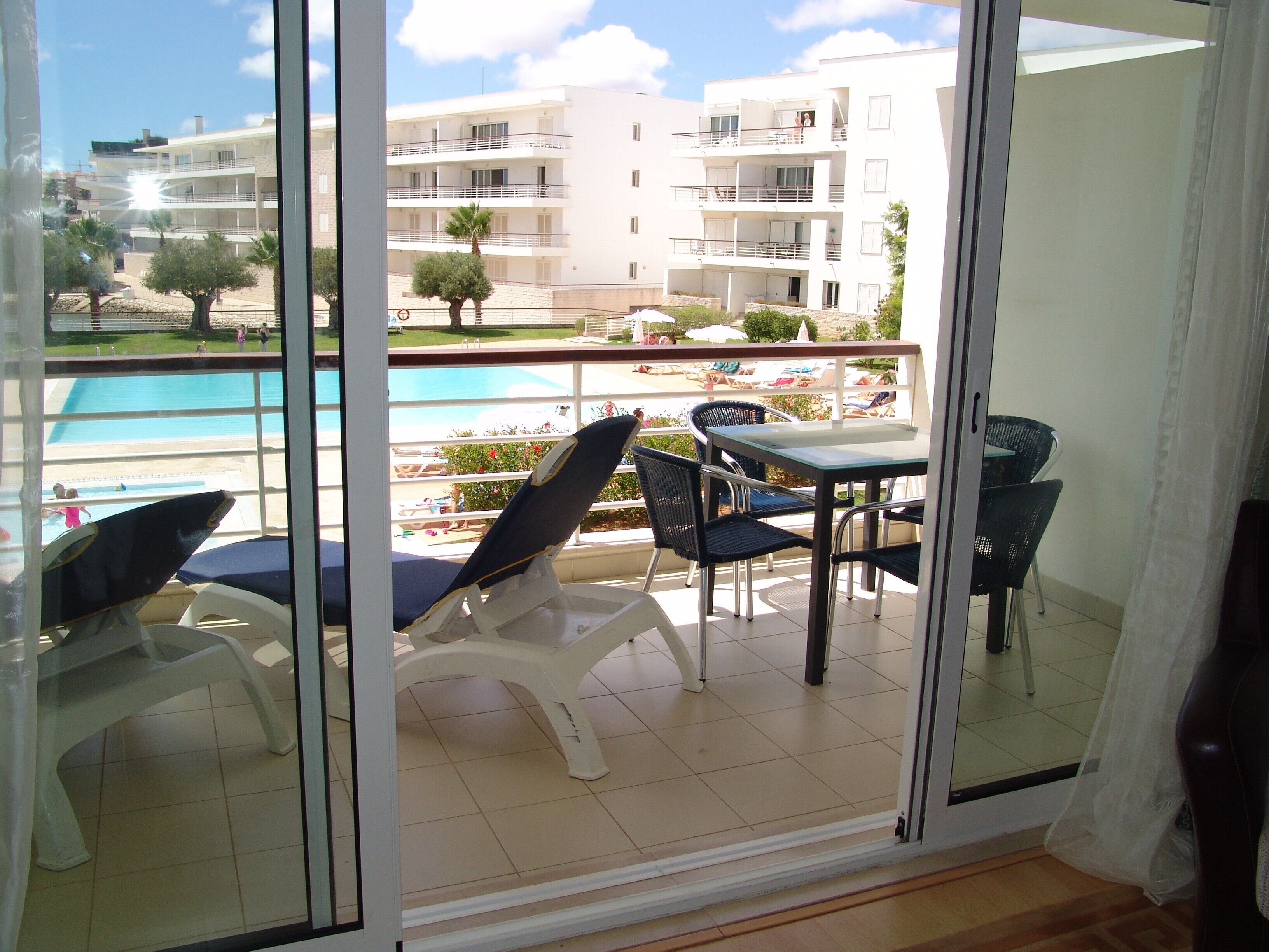 A balcony with a pool view, a table, and chairs.