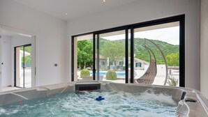 A hot tub with a view of a pool and mountains.