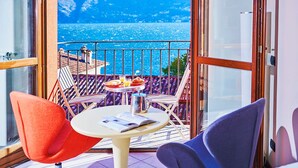 Un balcón con mesa, sillas y vista al mar y a las montañas.