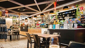 Un restaurante con zona de bar, mesas, sillas y diversos alimentos y bebidas a la vista.