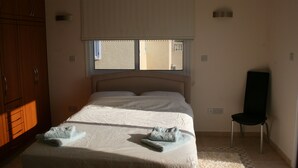 A bedroom with a bed, a chair, and a window. - Luxury Three Bed House With Private Pool, Garden and BBQ (Agios Georgios)
