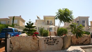 A residential area with a stone wall featuring the text "Warm Breeze." - Luxury Three Bed House With Private Pool, Garden and BBQ (Agios Georgios)
