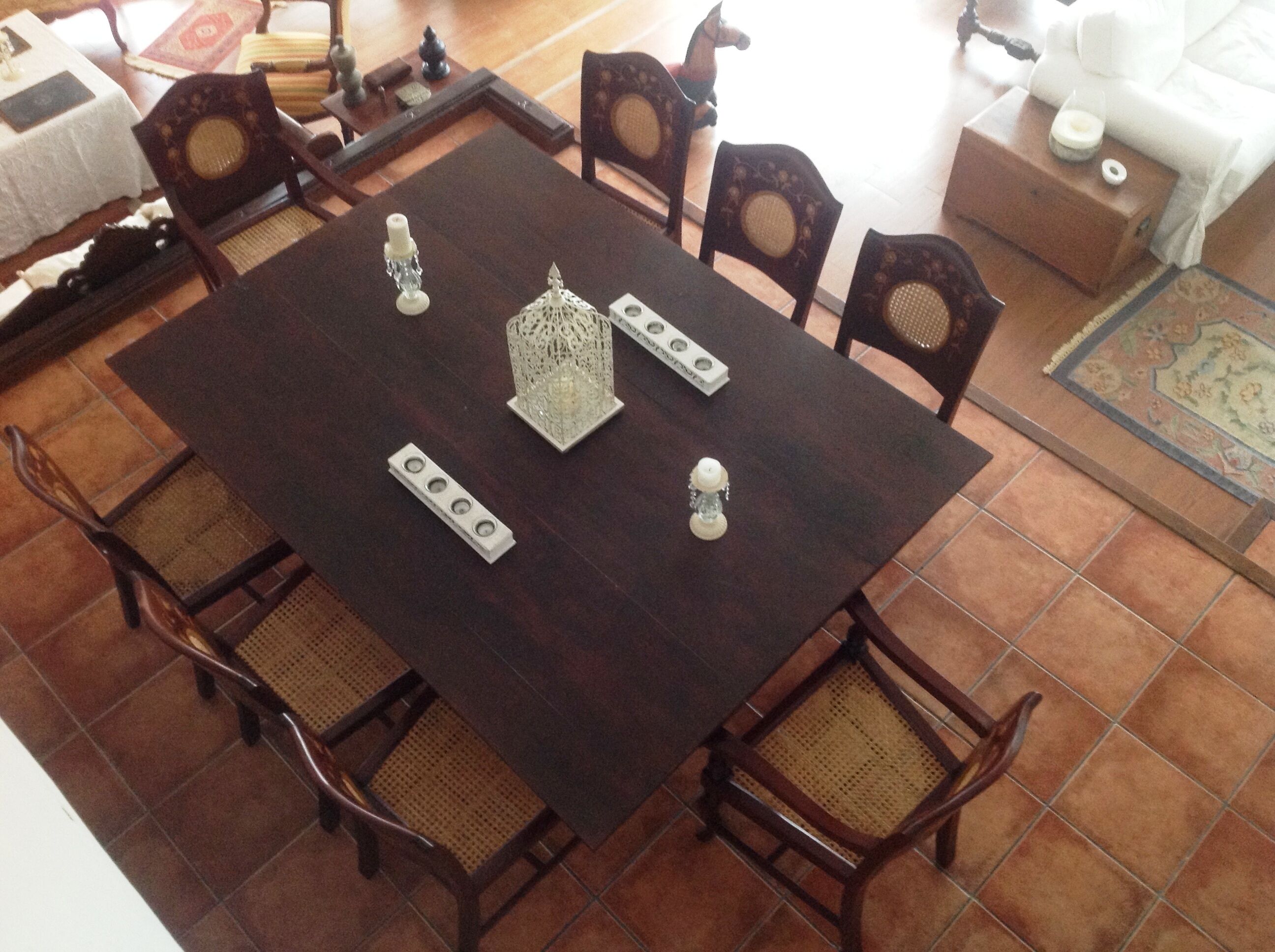 Zona pranzo con tavolo quadrato, quattro sedie e oggetti decorativi.