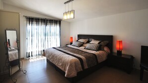 Une chambre à coucher avec un grand lit, deux lampes de chevet, un miroir et un luminaire au plafond.