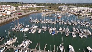 En småbåtshamn full av olika typer av båtar, inklusive segelbåtar och motorbåtar, låg förtöjda vid bryggorna.