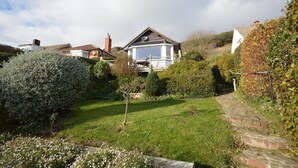 Il s’agit d’une propriété résidentielle dotée d’un jardin bien entretenu, d’un chemin en briques et d’une maison avec une grande fenêtre et une antenne parabolique.