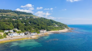 Une ville côtière avec des maisons construites sur une colline, une plage et une eau d’un bleu limpide.