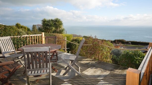 Une terrasse en bois, agréée de mobilier d’extérieur, offrant une vue sur la côte.