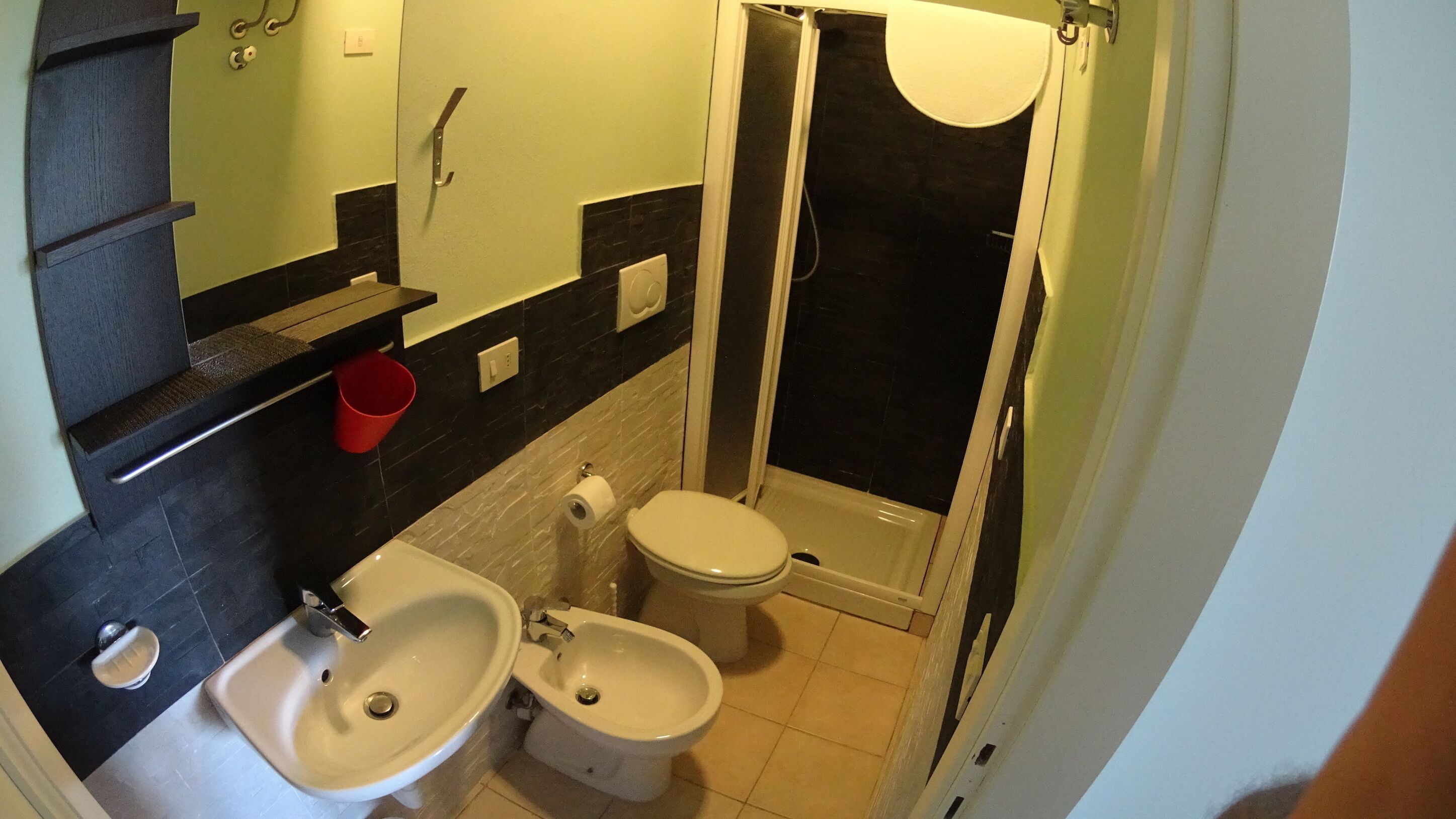 A compact bathroom with a sink, toilet, and shower.