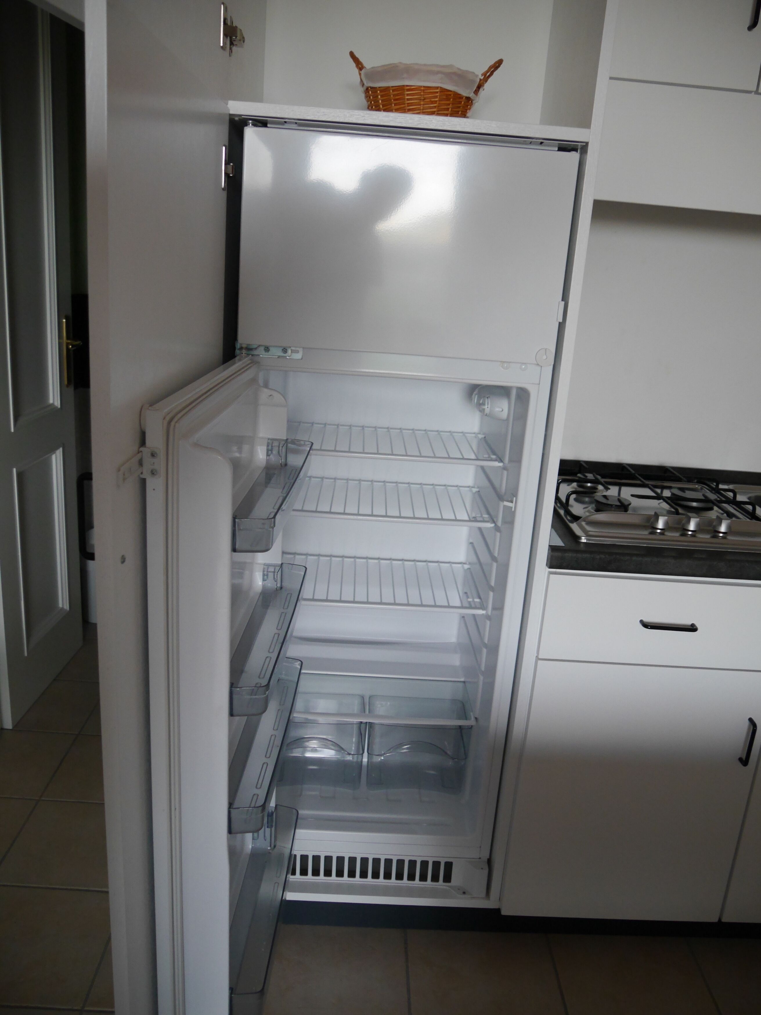An open refrigerator with multiple shelves and a basket on top.