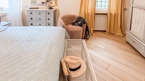 A bedroom with a large bed, a dresser, a chair, a mirror, and a window with curtains. - La Dolce Vita Boutique Apartment • Elegant • Terrace • Ponte Pietra (VERONA)