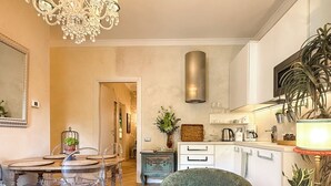 A modern kitchen with a chandelier, a dining area with a table and chairs, and a green armchair. - La Dolce Vita Boutique Apartment • Elegant • Terrace • Ponte Pietra (VERONA)