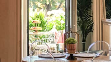 Comedor con candelabro, una mesa con sillas y vista a la vegetación exterior.