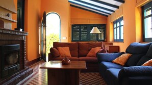 A cozy living room with a fireplace, a checkered floor, and a large window with blinds.