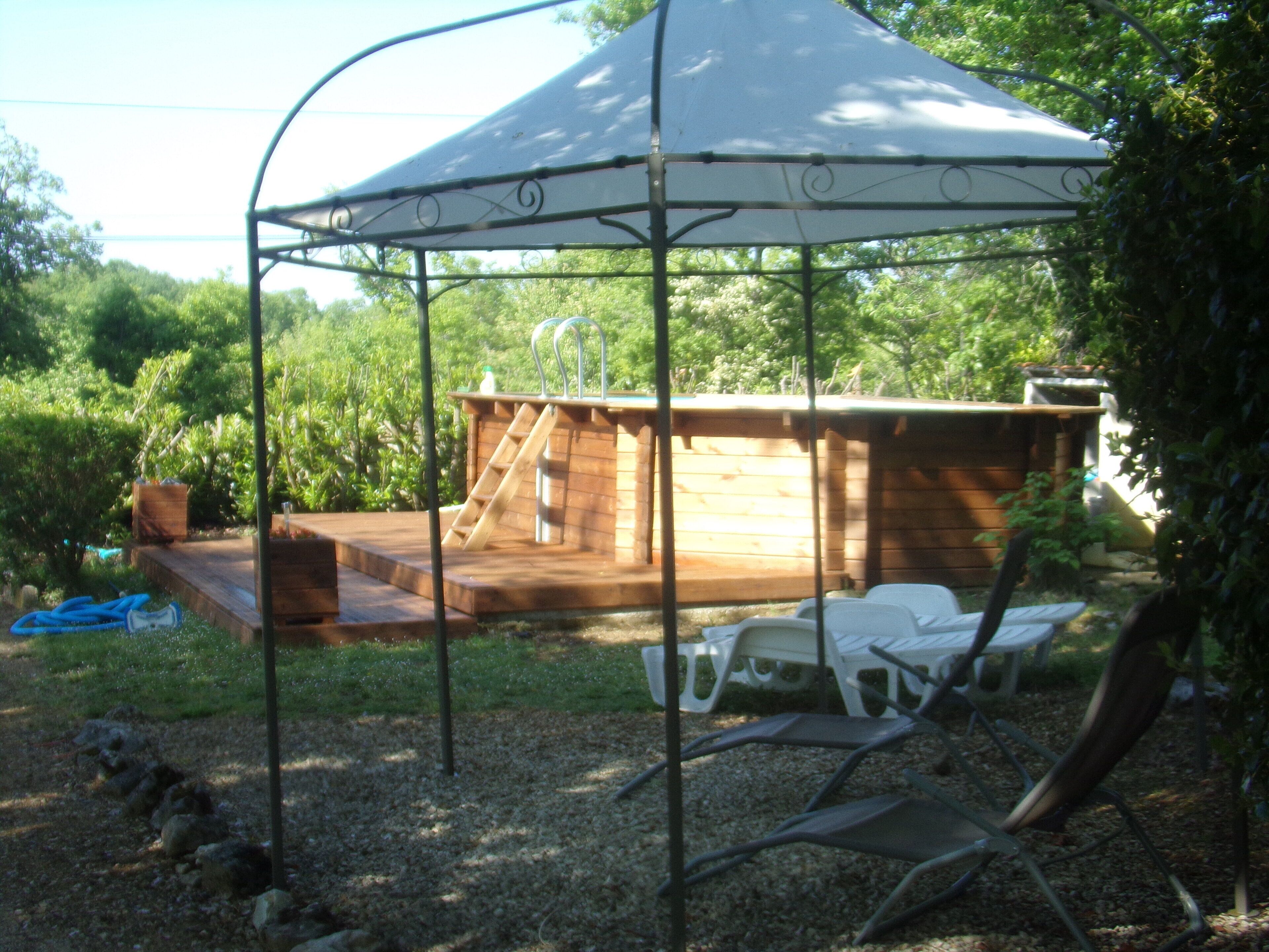 Un espace extérieur abrité doté d’une terrasse en bois, d’une petite piscine et d’un coin salon avec des chaises.