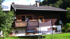 A wooden house with a balcony, a trampoline, and a satellite dish. - Ellmau: Quaint holiday home, 350 m to the mountain railway in the mountain doctor village (Ellmau)