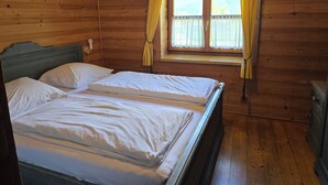 A wooden cabin room with a double bed, a window with yellow curtains, and a wooden dresser. - Ellmau: Quaint holiday home, 350 m to the mountain railway in the mountain doctor village (Ellmau)