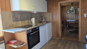 A compact kitchen with wooden cabinets, a built-in oven, and a sink. - Ellmau: Quaint holiday home, 350 m to the mountain railway in the mountain doctor village (Ellmau)