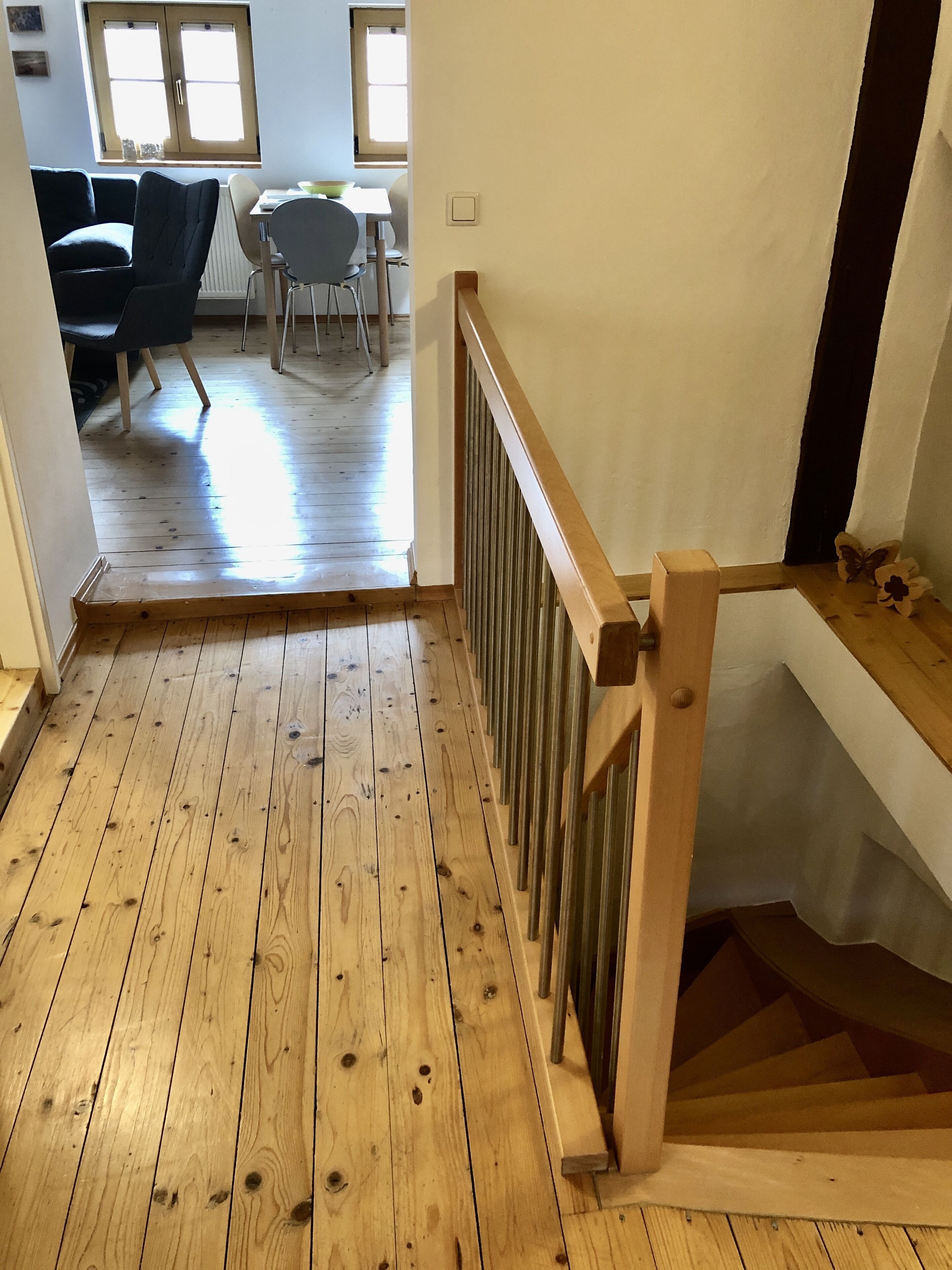 Eine Holztreppe mit Geländer, die zu einer Zwischenebene führt.