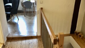 Eine Holztreppe mit Geländer, die zu einer Zwischenebene führt.