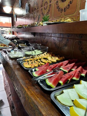 A buffet with various food items including watermelon, cheese, and other dishes. - Pousada Chiclé (Itatiaia)