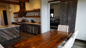 A dining area with a large wooden table and white upholstered chairs. - Ranches at Belt Creek (Belt)