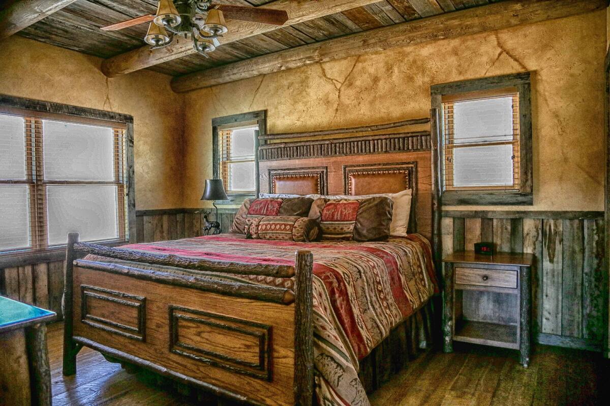 A rustic bedroom with a wooden bed, two nightstands, and a ceiling fan.