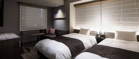 A hotel room with two beds, a small table, a sofa, and a TV.