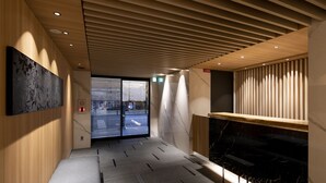 Un vestíbulo moderno con techo de madera, un mostrador de recepción de mármol y un cuadro abstracto grande en la pared.