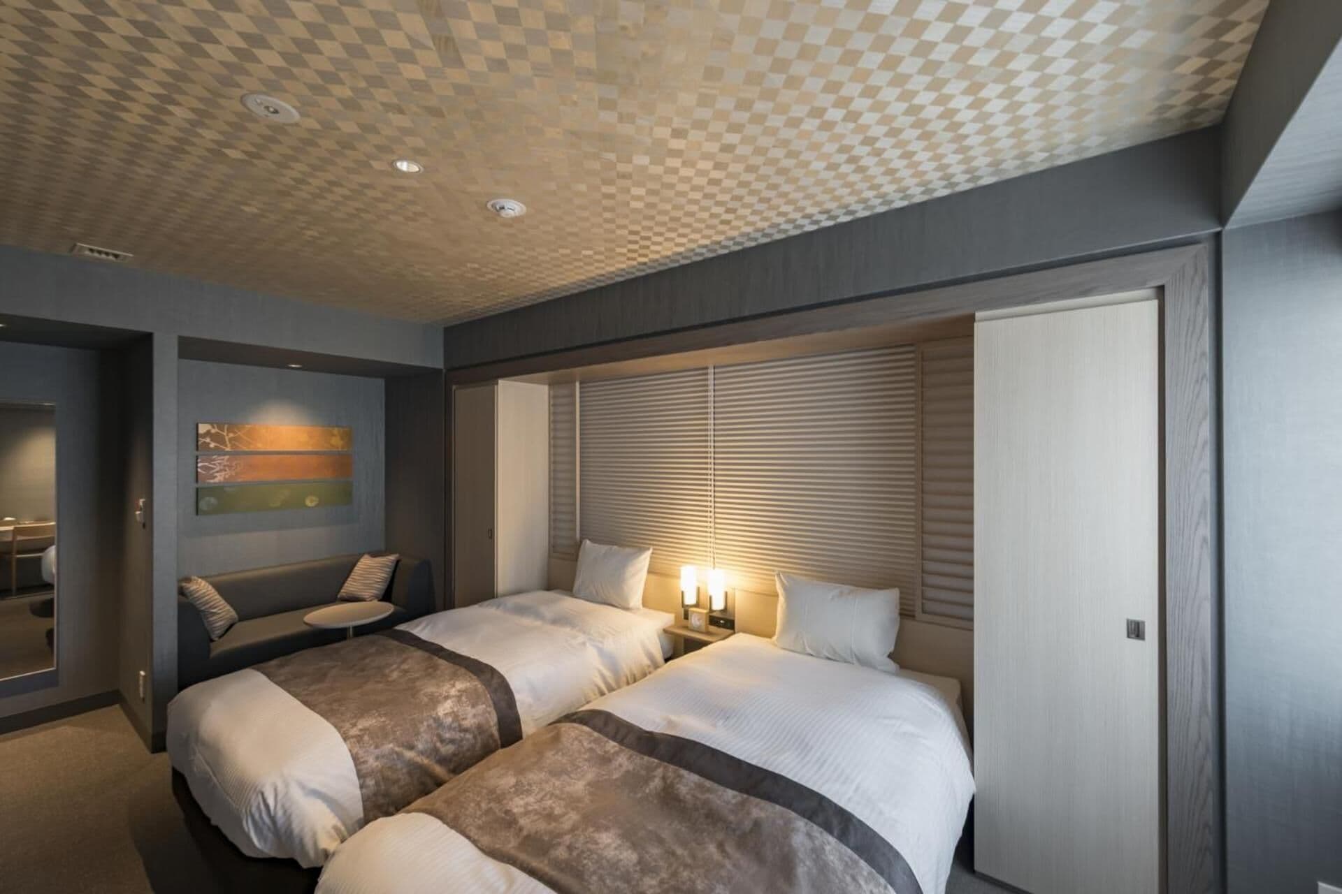 A hotel room with two beds, a seating area, and a large wardrobe.