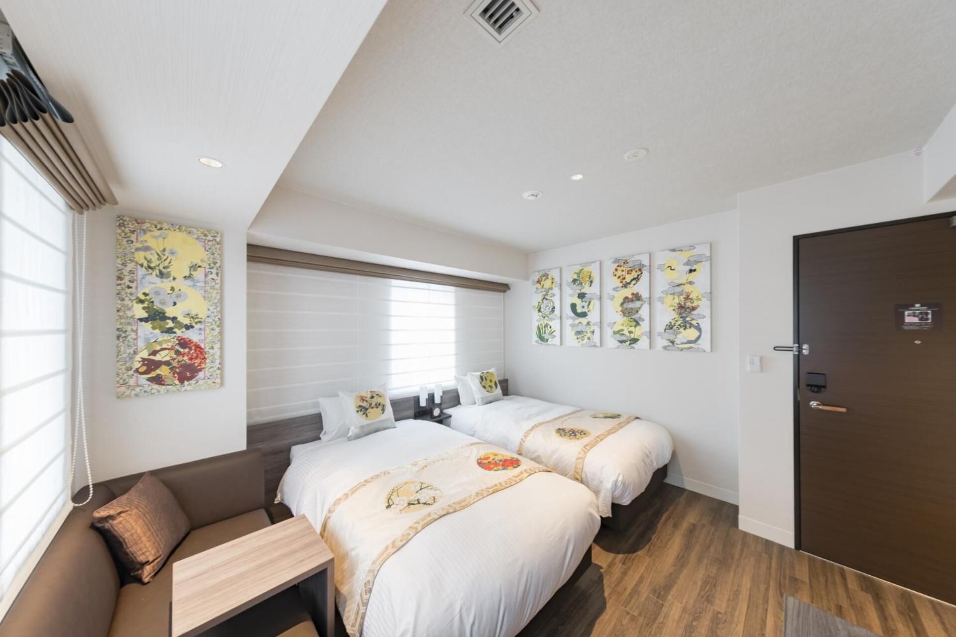 Ein Hotelzimmer mit zwei Betten, einem Sofa und Holzboden.