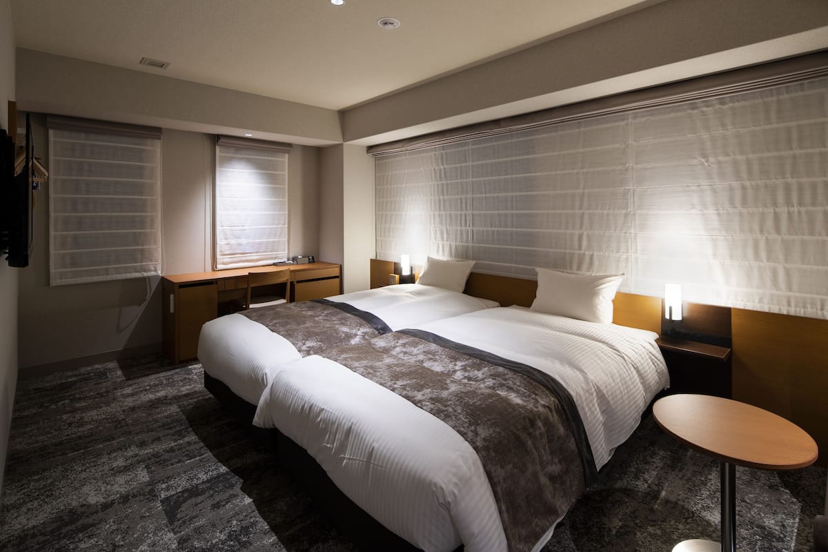 A modern hotel room with a large bed, a desk, and a small table.