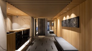 Un pasillo moderno de hotel con un banco de madera, una recepción y una obra de arte en la pared.