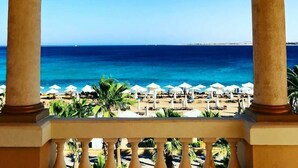 A balcony with a view of the sea, palm trees, and beach umbrellas. - Luxury 4BD Villa with Pool in Hurghada (Hurghada)