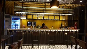 A bar area with a counter, stools, a refrigerator, and a patterned floor. - Hotel Snow Angeles (Angeles City)
