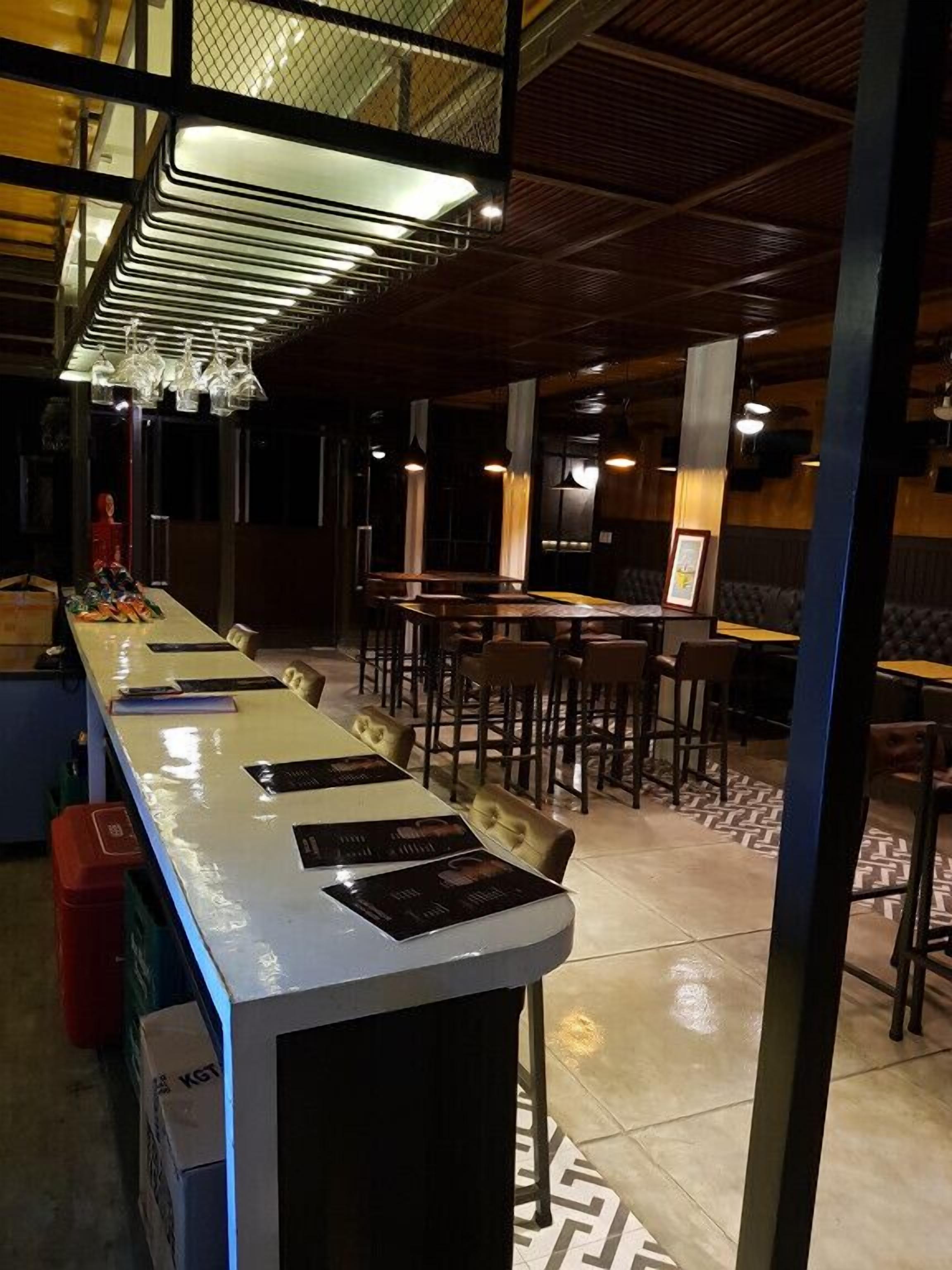 A restaurant with a long counter, multiple tables, and chairs.