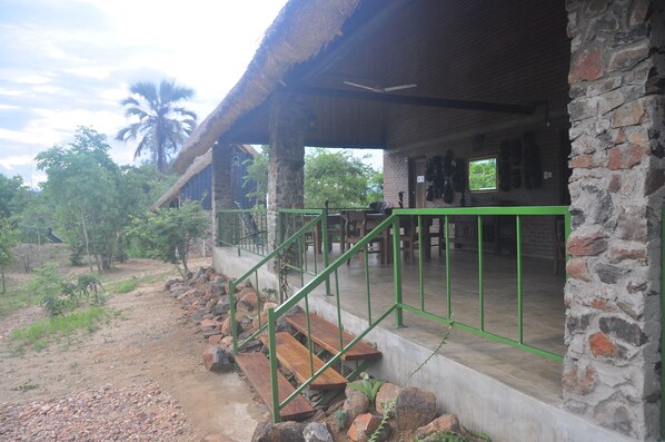 A rustic building with a thatched roof, stone walls, and a green metal railing.