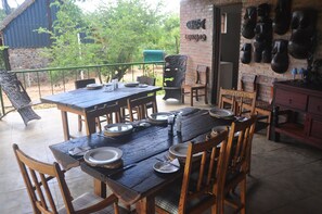 An outdoor dining area with a wooden table set for four, surrounded by wooden chairs.