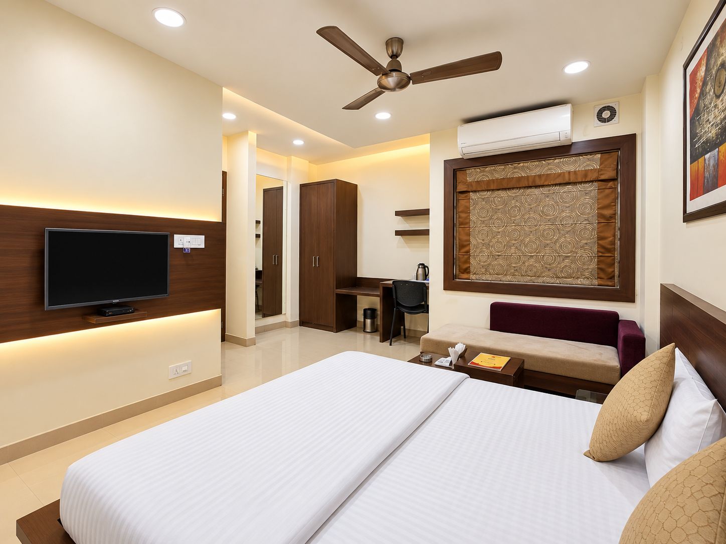 A hotel room with a bed, a desk, a television, and a ceiling fan.