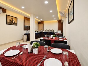 A dining area with tables set for four, equipped with plates, cutlery, and glasses. - Hotel Alankar Palace (Bhopal)