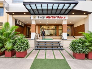 The entrance of Hotel Alankar Palace with a modern design, featuring a glass canopy, a reception desk, and a staircase leading to the entrance. - Hotel Alankar Palace (Bhopal)