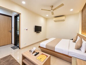 A hotel room with a bed, a television, a ceiling fan, and an air conditioning unit. - Hotel Alankar Palace (Bhopal)