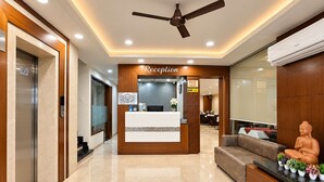 A reception area with a reception desk, a ceiling fan, an elevator, and a Buddha statue.
