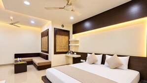 A modern hotel room with a large bed, a seating area, and a ceiling fan.