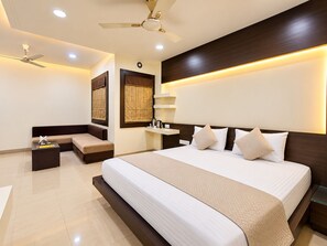 A modern hotel room with a large bed, a seating area, and a ceiling fan. - Hotel Alankar Palace (Bhopal)